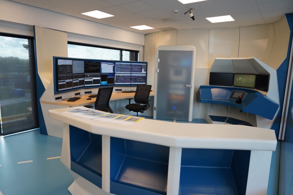 An image of a modern railway workplace of an interlocking system. Big screens and a modern counter.