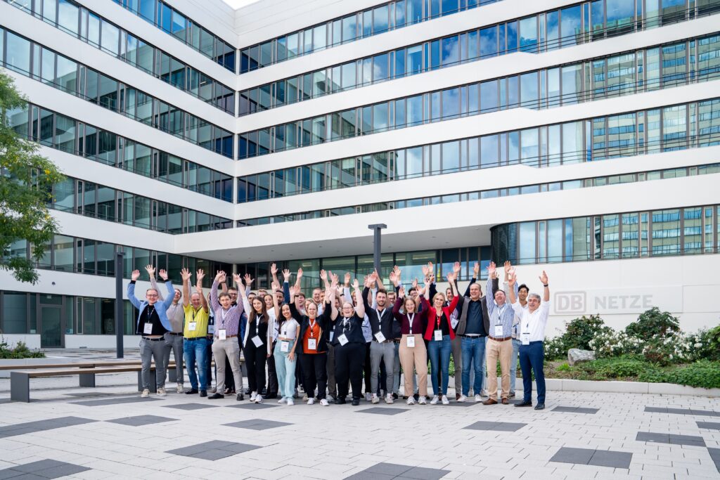 An image of a large group of young persons infront of a modern office building